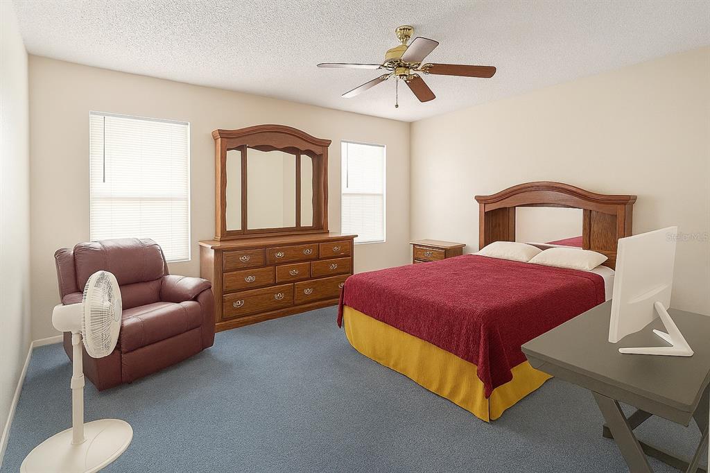 A bedroom with blue carpet, a wooden bed frame, a dresser with a mirror, and furniture — 2417 NE 6TH STREET UNIT 8, OCALA, FL