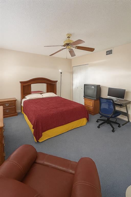 A bedroom features a bed with a red cover, a desk, a television, and carpet — 2417 NE 6TH STREET UNIT 8, OCALA, FL