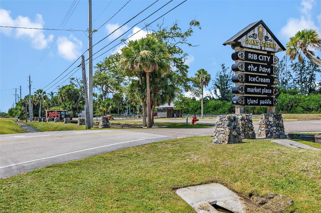 A sign for Grant Station stands beside a road with palm trees and a parking lot — 5390 US HIGHWAY 1, GRANT VALKARIA, FL