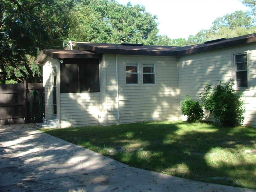 A beige house with a screened-in porch and a concrete driveway surrounded by trees — 11709 HOYT AVENUE, TAMPA, FL