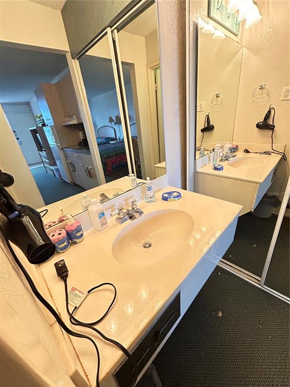 A bathroom vanity with a white countertop, oval sink, and large mirror — 43420 HIGHWAY 27 UNIT 455, DAVENPORT, FL