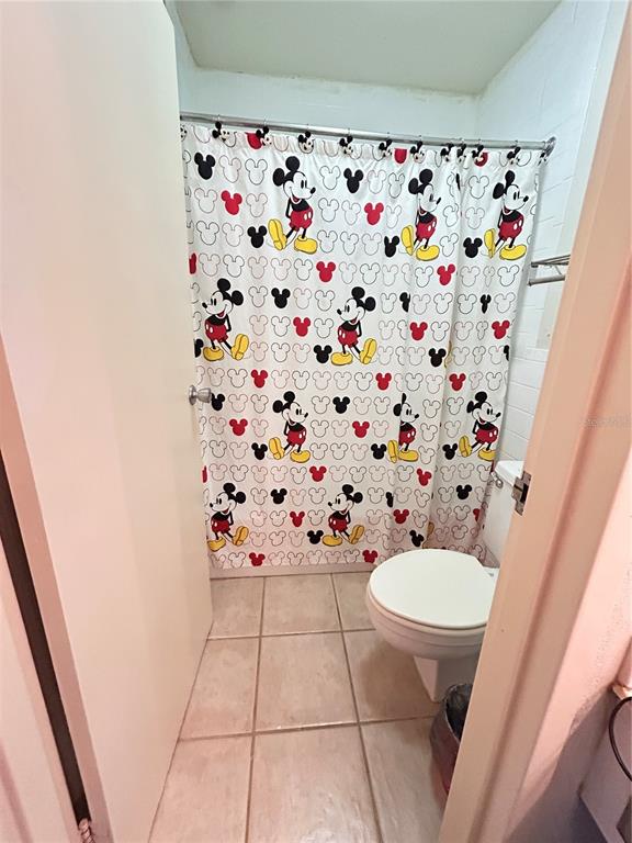 A small bathroom features a Mickey Mouse shower curtain and a white toilet — 43420 HIGHWAY 27 UNIT 455, DAVENPORT, FL