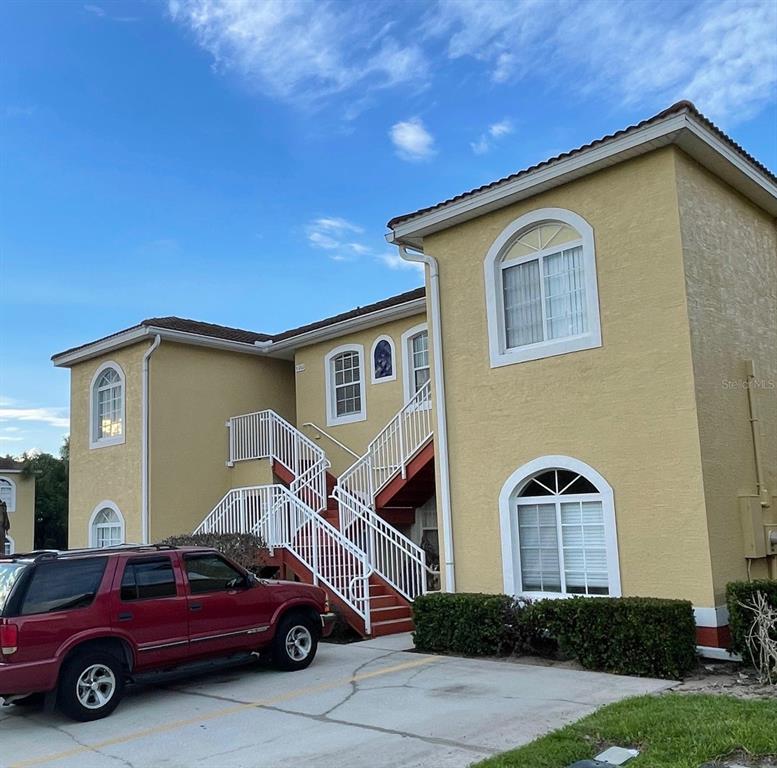 A two-story yellow stucco apartment building with white railings and an exterior staircase — 9202 LAKE MARION GOLF RESORT UNIT A, KISSIMMEE, FL