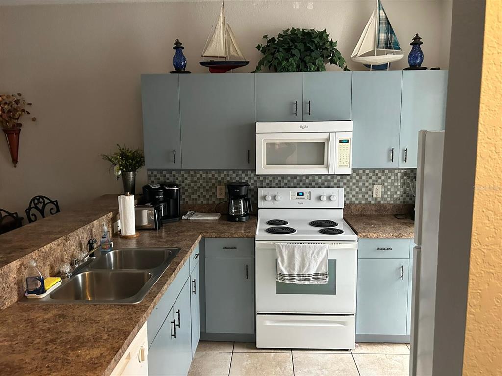 A kitchen features light blue cabinets, a white stove, a microwave, and brown countertops — 9202 LAKE MARION GOLF RESORT UNIT A, KISSIMMEE, FL