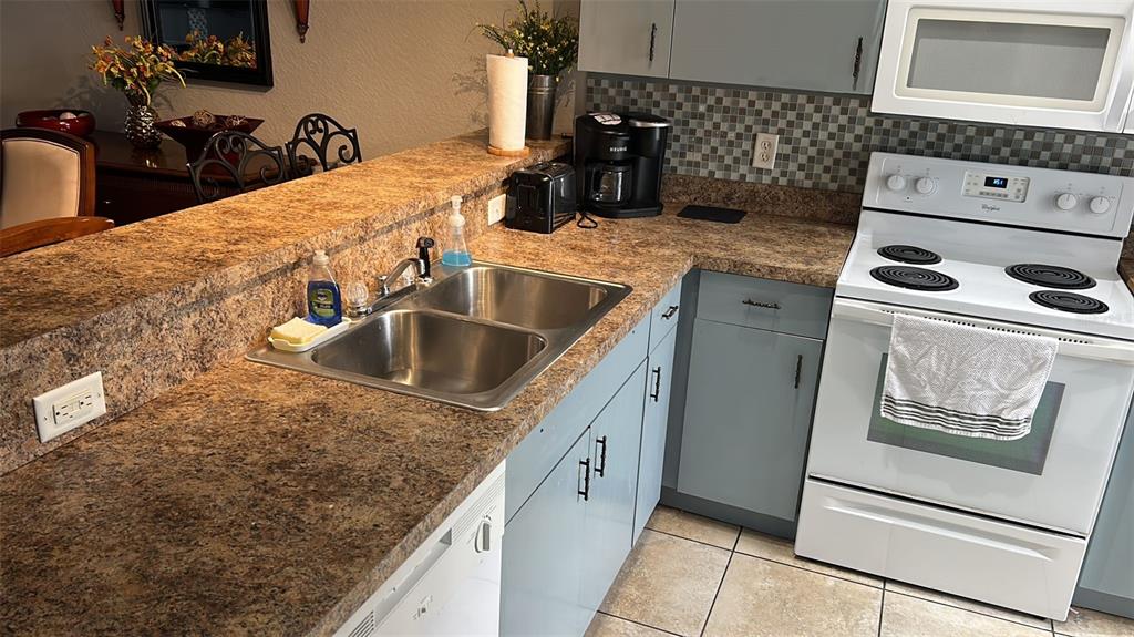 A kitchen features light blue cabinets, a double sink, and brown laminate countertops — 9202 LAKE MARION GOLF RESORT UNIT A, KISSIMMEE, FL