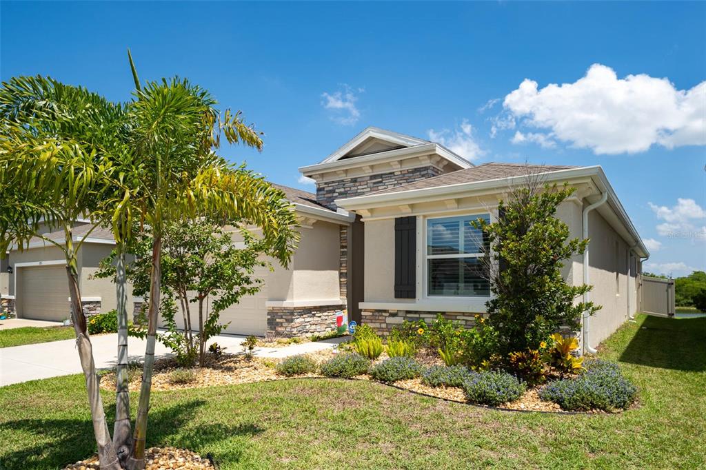 A single-story house with a beige stucco exterior, stone accents, and a palm tree — 3719 LIVELY CORAL PLACE, BRADENTON, FL