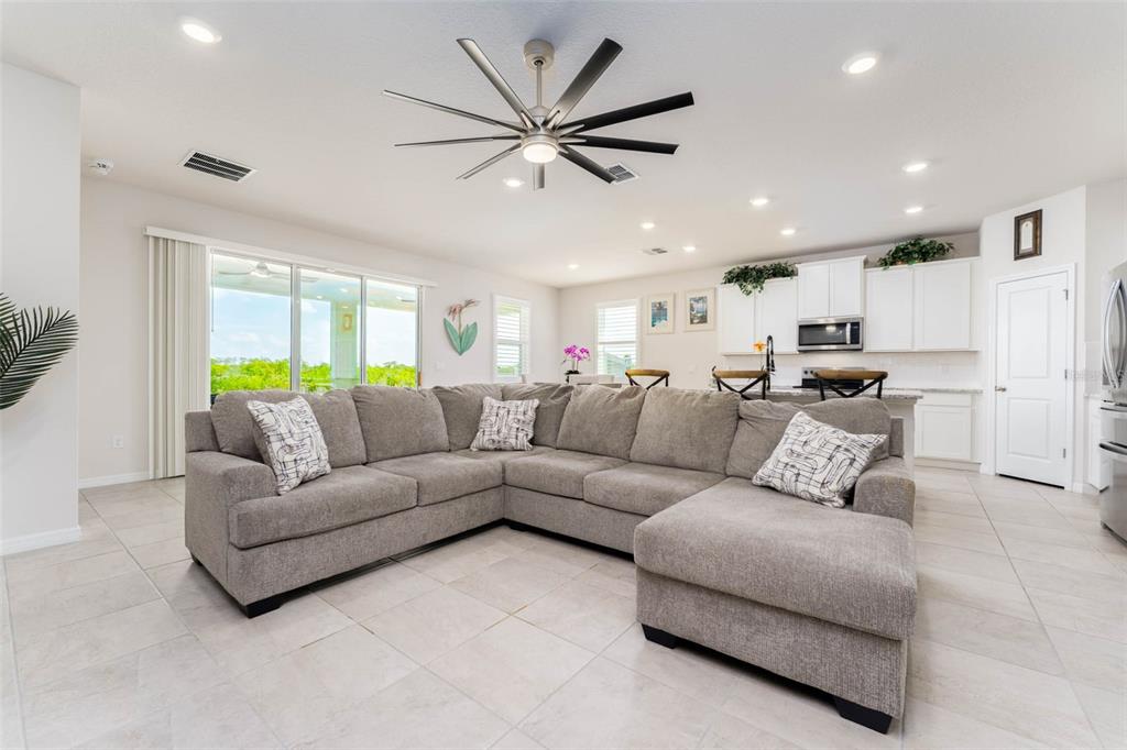 A spacious living room features a large gray sectional sofa and an open-concept kitchen — 3719 LIVELY CORAL PLACE, BRADENTON, FL