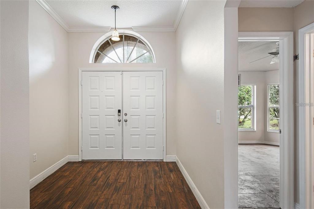 An entryway with wood-look flooring, white double doors, and an arched transom window above — 4007 HARBOR LAKE DRIVE, LUTZ, FL