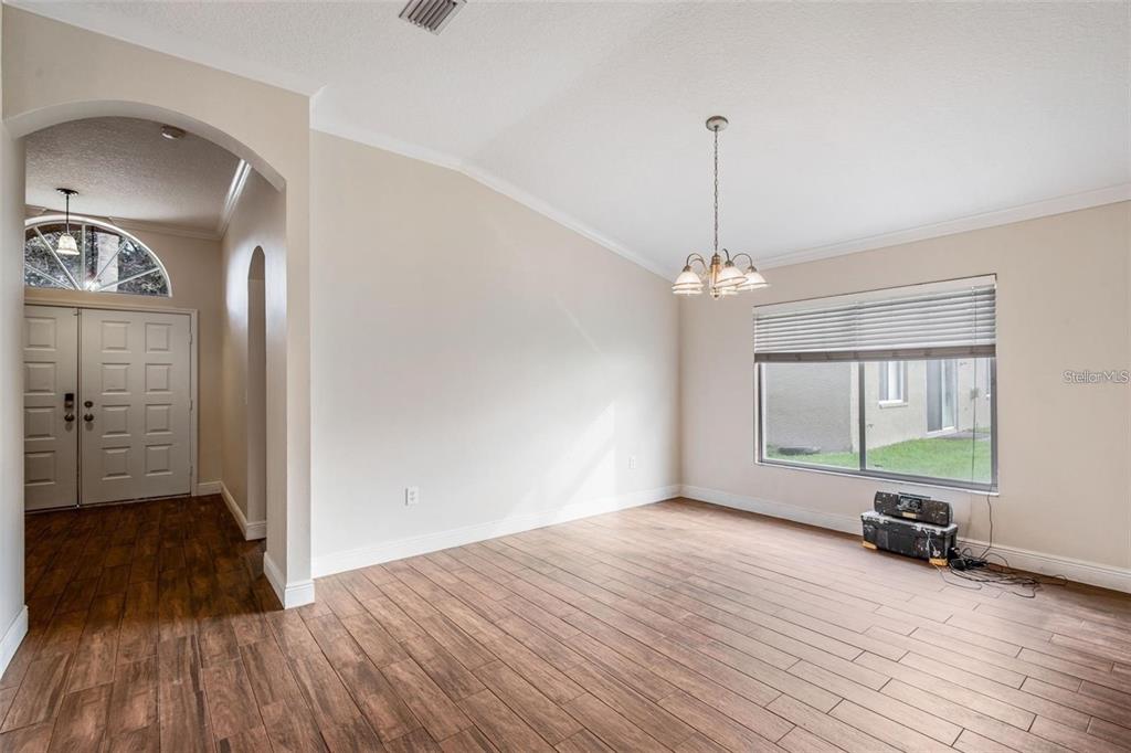 A dining room with wood-look tile flooring, a vaulted ceiling, and a chandelier — 4007 HARBOR LAKE DRIVE, LUTZ, FL