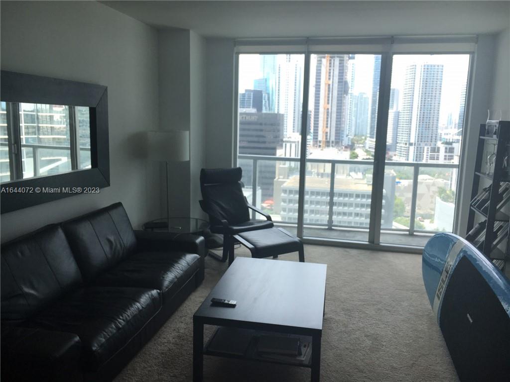 A living room features a black leather sofa, a matching armchair, and floor-to-ceiling city views — 55 SE 6 ST # 2006, Miami FL 33131, MIAMI, FL