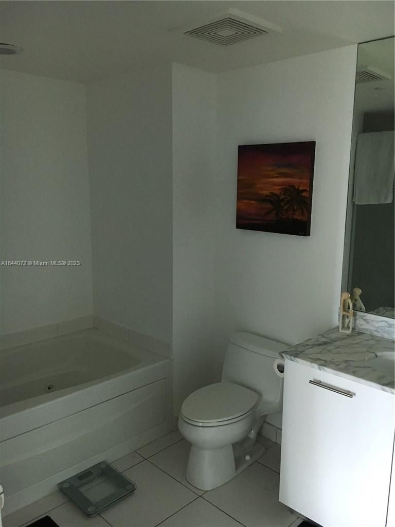 A bathroom features a white vanity with a marble countertop, a toilet, and a bathtub — 55 SE 6 ST # 2006, Miami FL 33131, MIAMI, FL