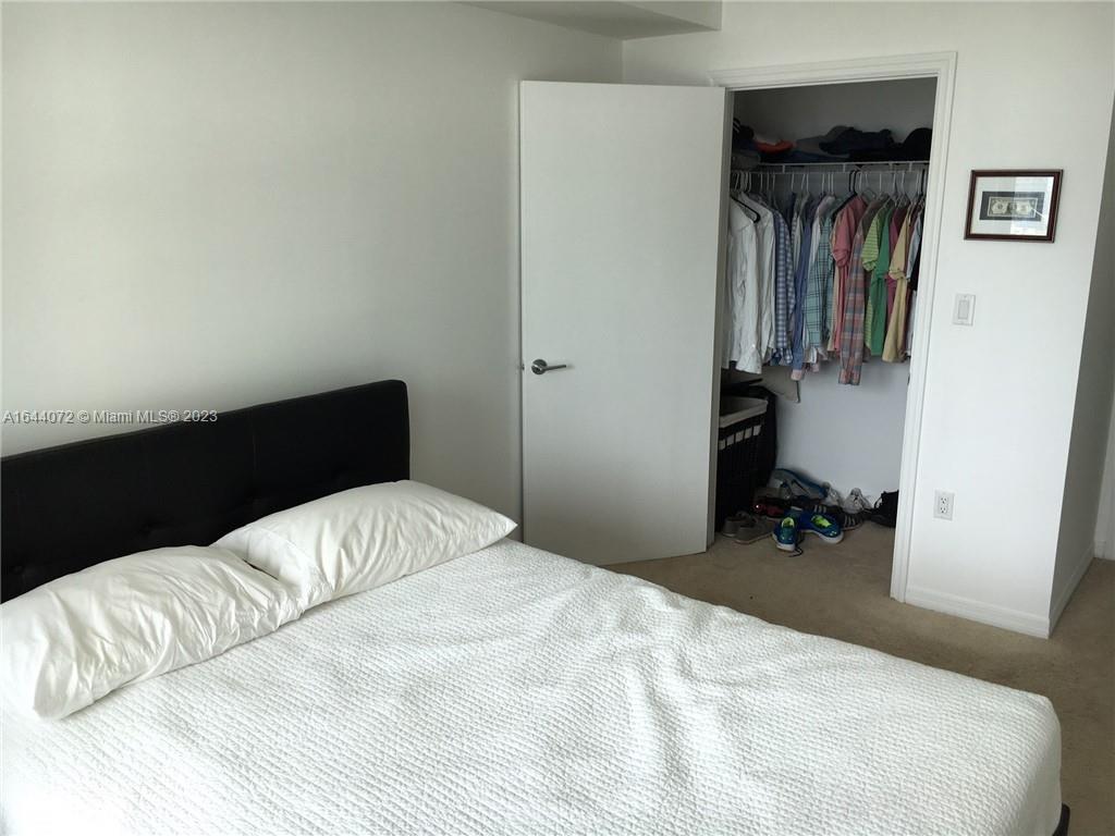 A bedroom features a bed with a black headboard and an open closet with hanging clothes — 55 SE 6 ST # 2006, Miami FL 33131, MIAMI, FL
