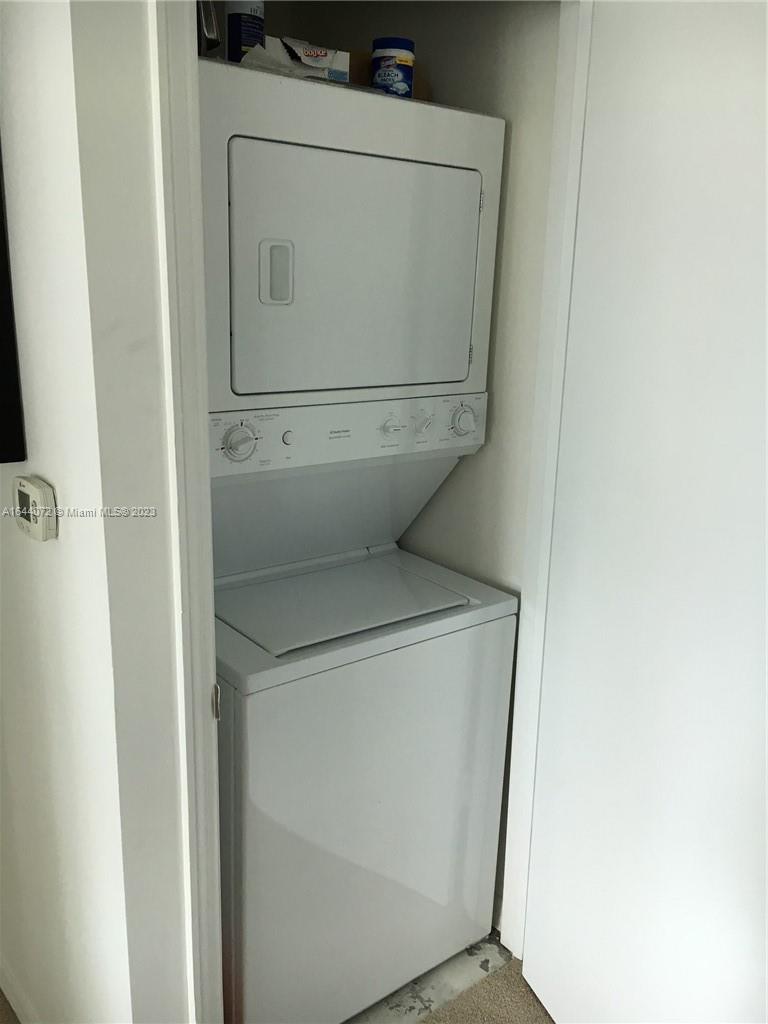 A white stacked washer and dryer unit is installed inside a closet — 55 SE 6 ST # 2006, Miami FL 33131, MIAMI, FL