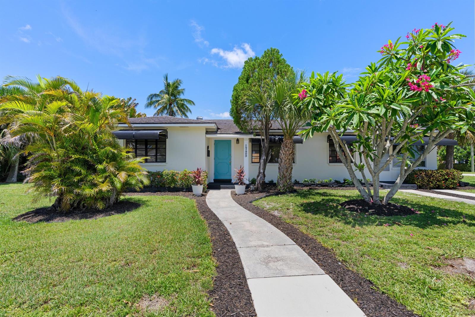 A single-story house with a light-colored exterior, a blue front door, and lush landscaping — 1725 N Lakeside Drive, FL 33460, FL