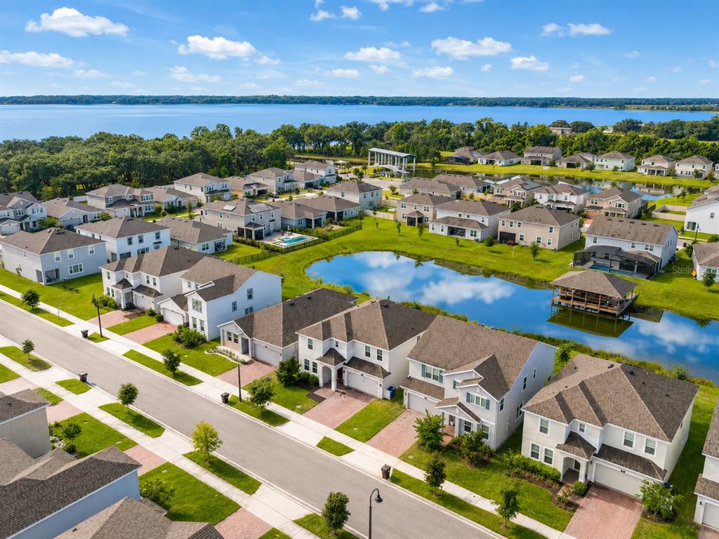 An aerial view of a suburban neighborhood with houses surrounding a central pond and lake — 5046 DOWN COURT, ST CLOUD, FL