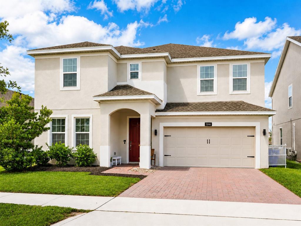 A two-story beige house features a red front door, a two-car garage, and a driveway — 5046 DOWN COURT, ST CLOUD, FL