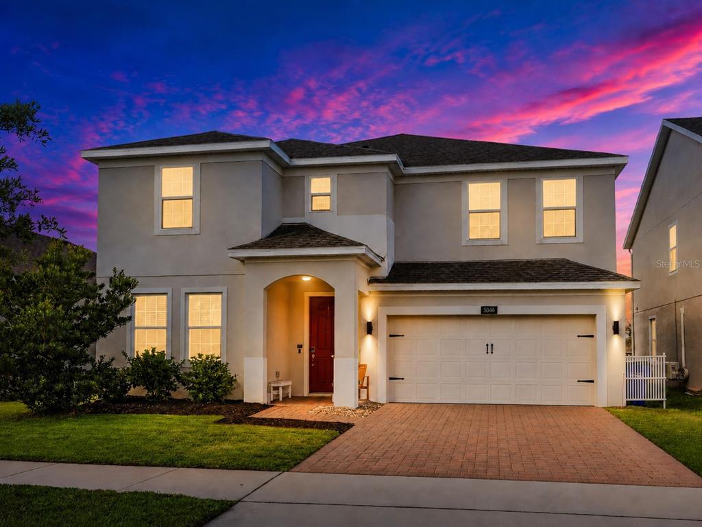A two-story suburban house with a brick driveway, a red front door, and a garage — 5046 DOWN COURT, ST CLOUD, FL