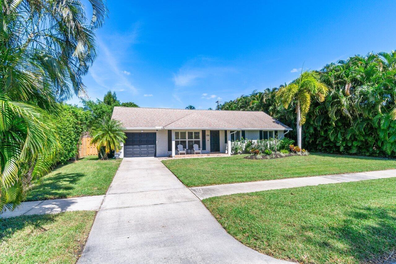 A single-story house with a gray garage, a concrete driveway, and lush landscaping — 1315 Fulmar Drive, Delray Beach FL 33444, DELRAY BEACH, FL