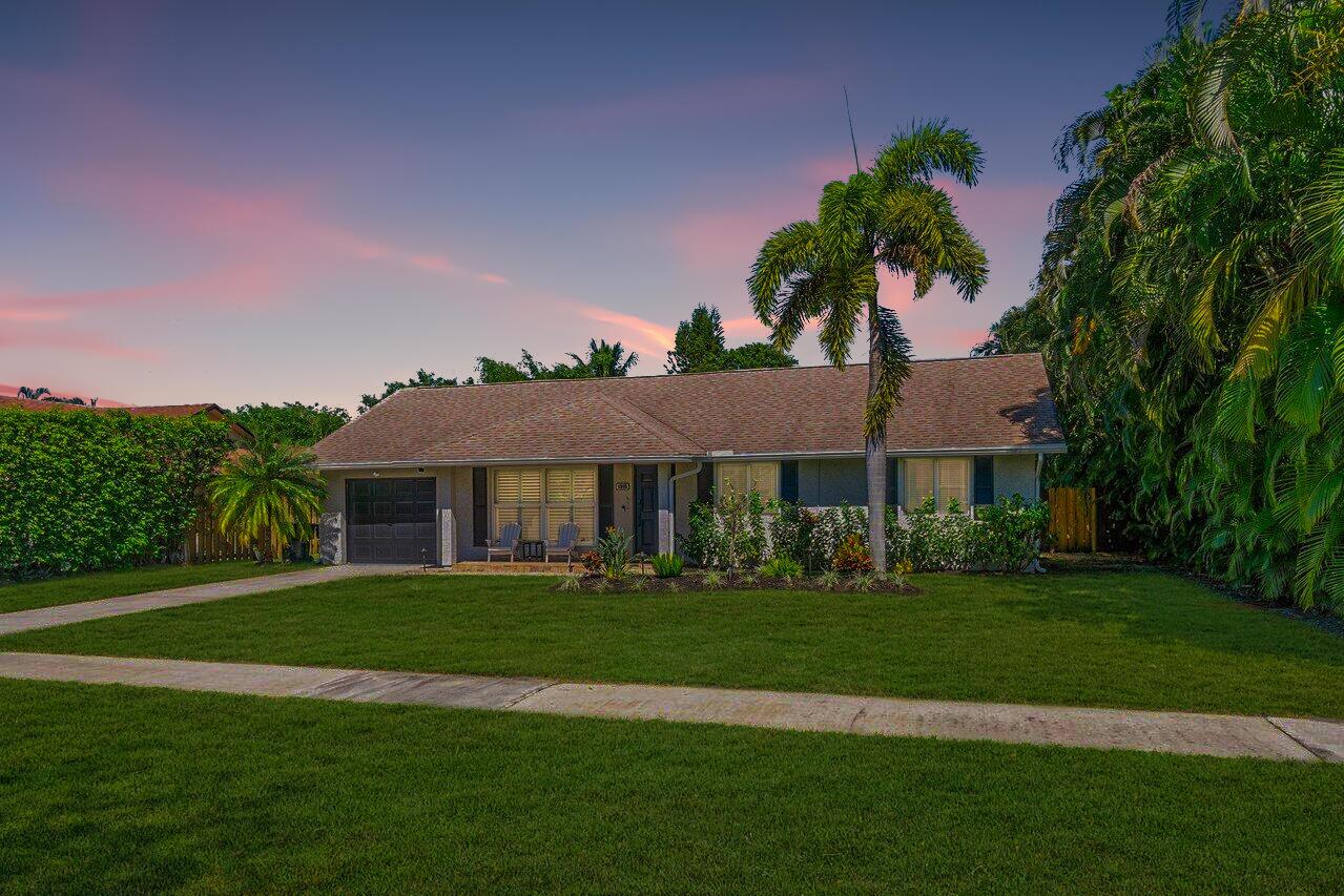 A single-story house with a lawn, palm tree, and attached garage under a sunset sky — 1315 Fulmar Drive, Delray Beach FL 33444, DELRAY BEACH, FL