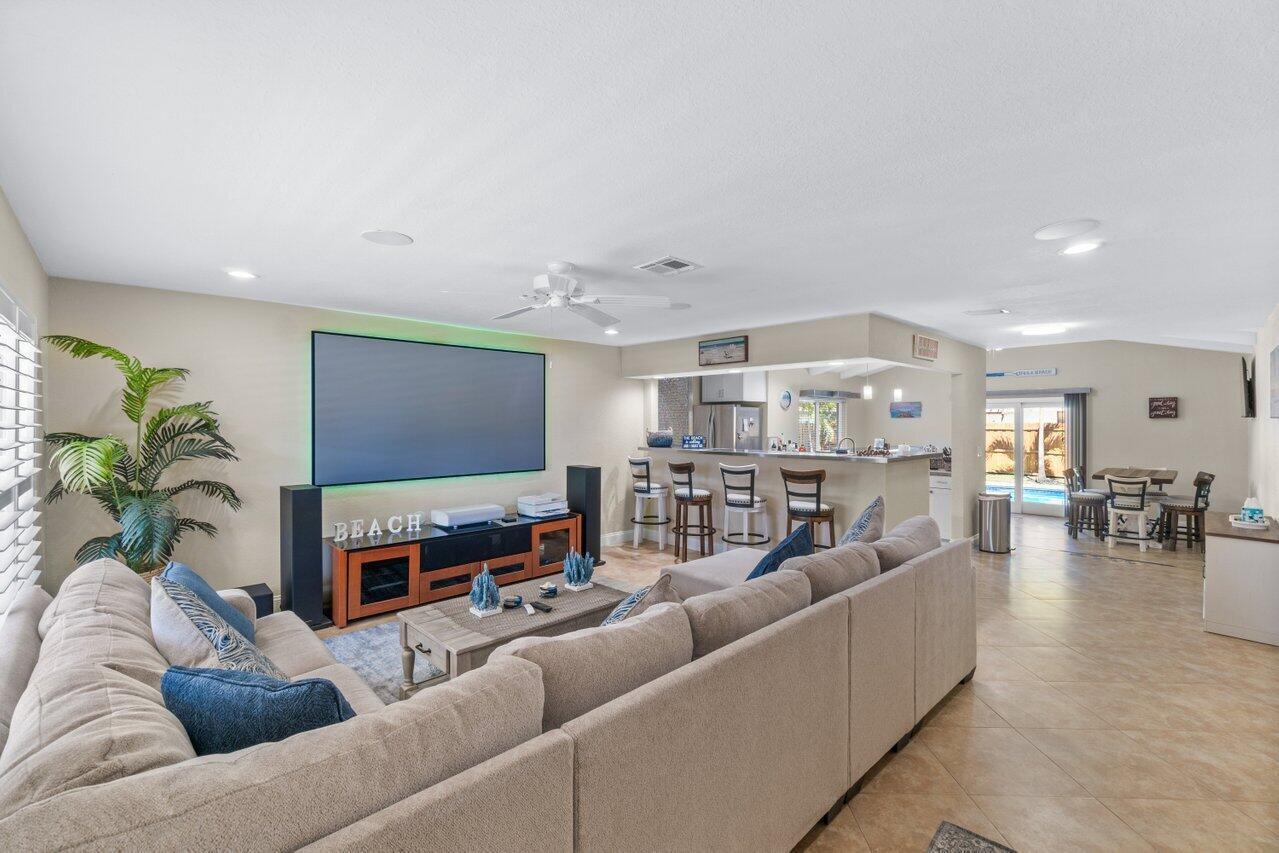 A living room with a large sectional sofa, television, and an open kitchen with bar seating — 1315 Fulmar Drive, Delray Beach FL 33444, DELRAY BEACH, FL