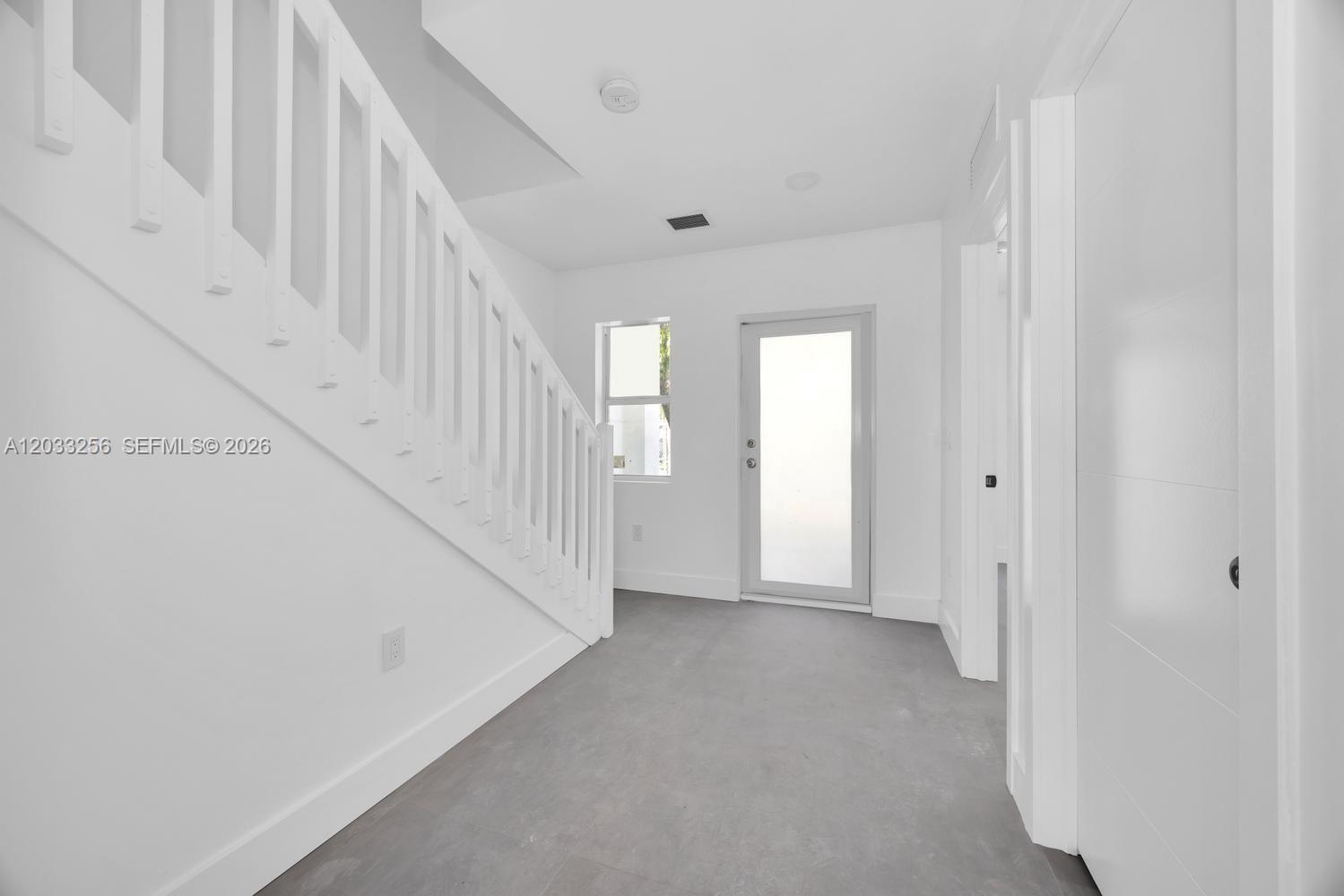 An entryway features a white staircase, a glass-paneled door, and gray tile flooring — 2780 NW 44th St, Miami FL 33142, MIAMI, FL