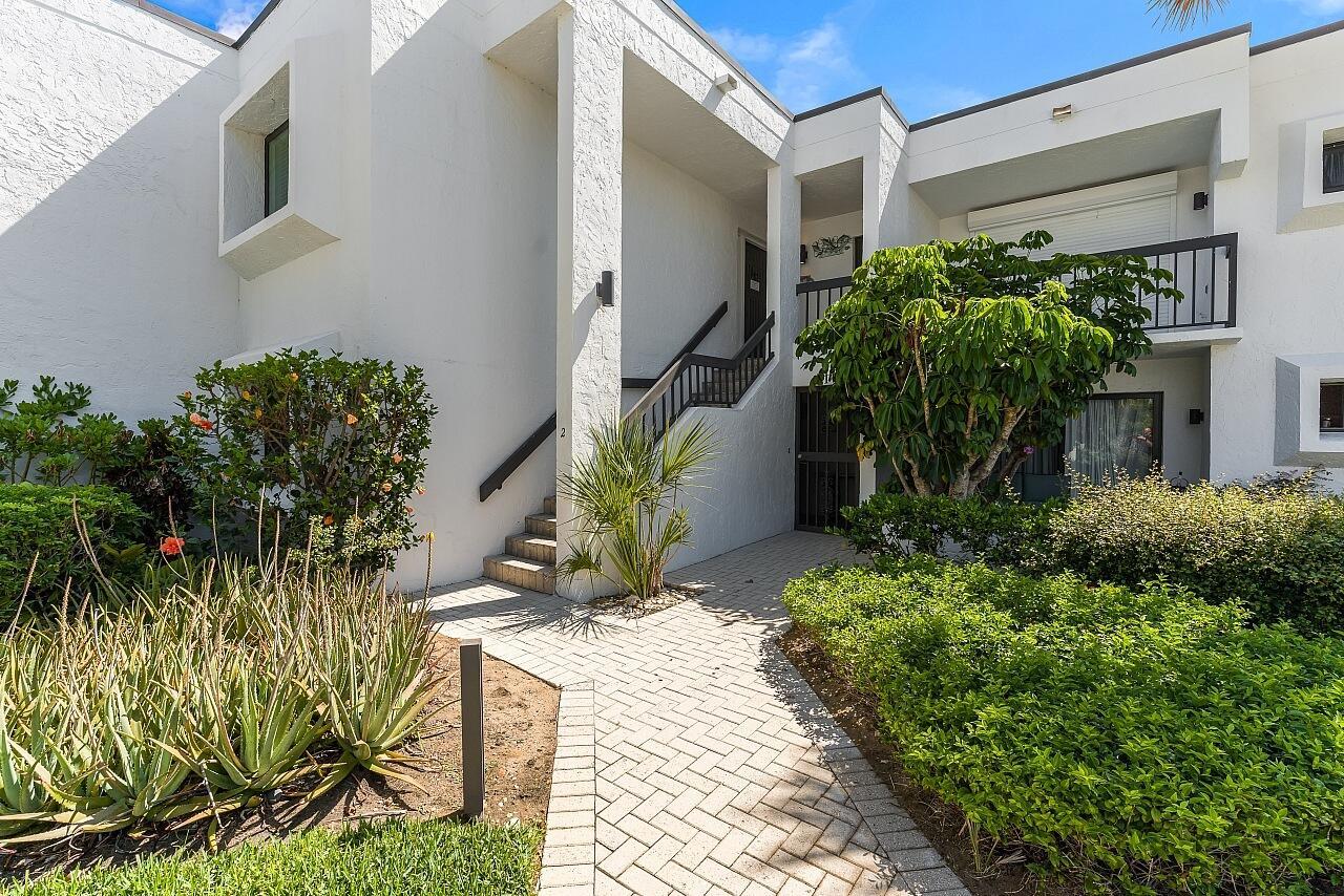 A two-story white stucco building features a brick walkway leading to an outdoor staircase — 5790 Highway A1a # 2a, Vero Beach FL 32963, VERO BEACH, FL