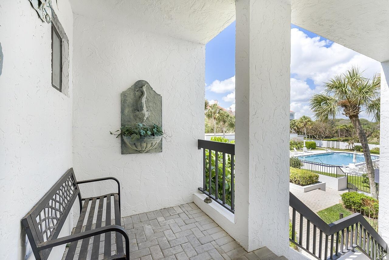 A covered balcony features a metal bench, a wall-mounted fountain, and views of a pool — 5790 Highway A1a # 2a, Vero Beach FL 32963, VERO BEACH, FL
