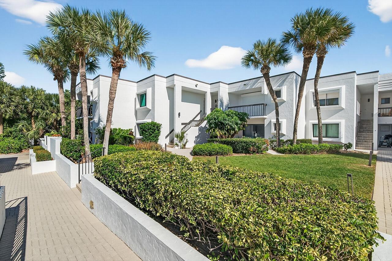 A two-story white apartment complex features palm trees, manicured hedges, and a paved walkway — 5790 Highway A1a # 2a, Vero Beach FL 32963, VERO BEACH, FL
