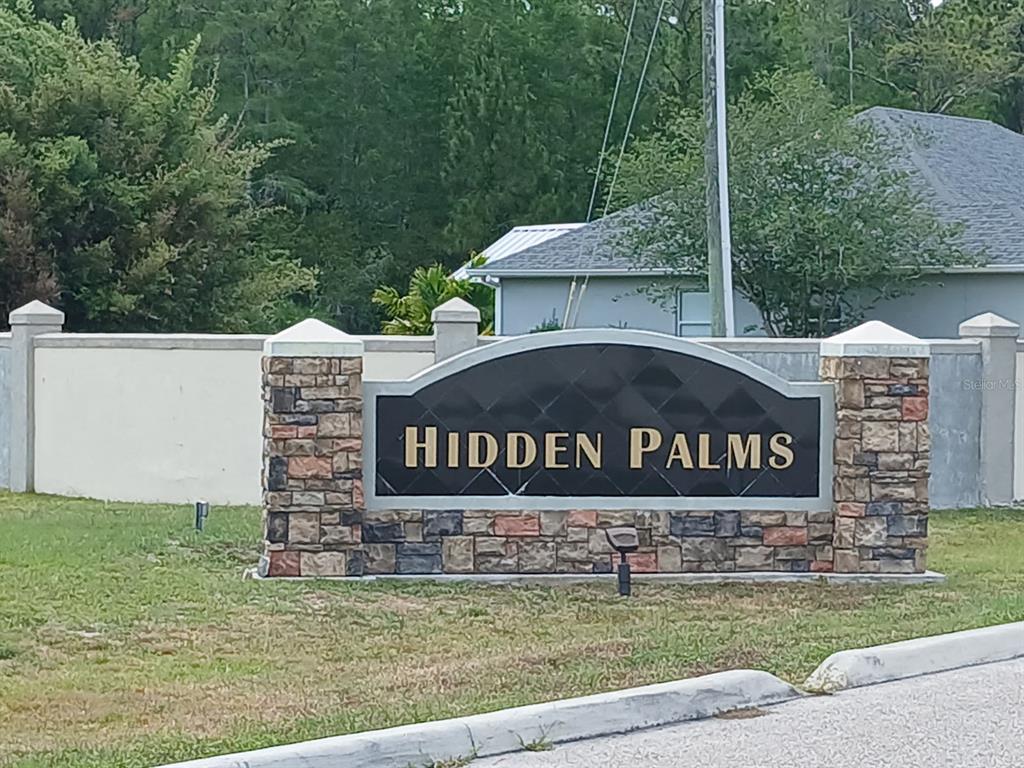 A stone and black metal sign marks the entrance to the Hidden Palms community — 1102 HIDDEN PALMS DRIVE, DAVENPORT, FL