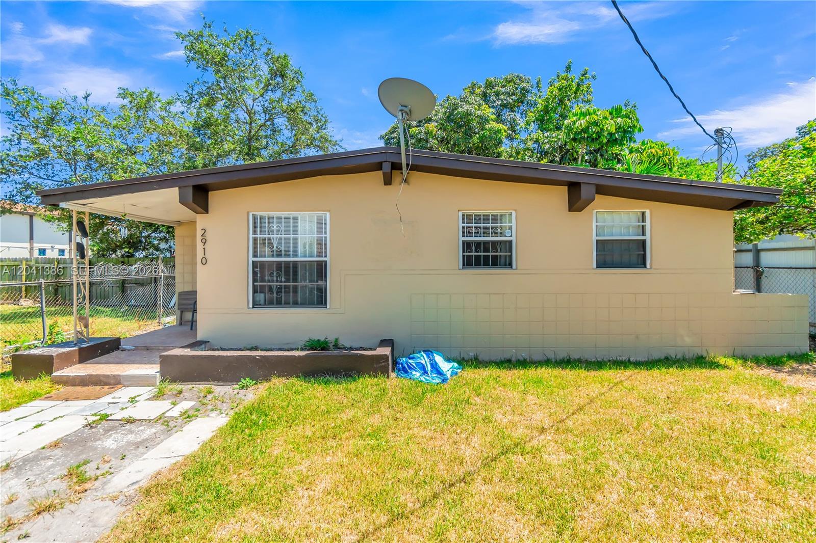 A single-story house with a tan stucco exterior, a satellite dish, and a front lawn — 2910 NW 47th St, Miami FL 33142, MIAMI, FL
