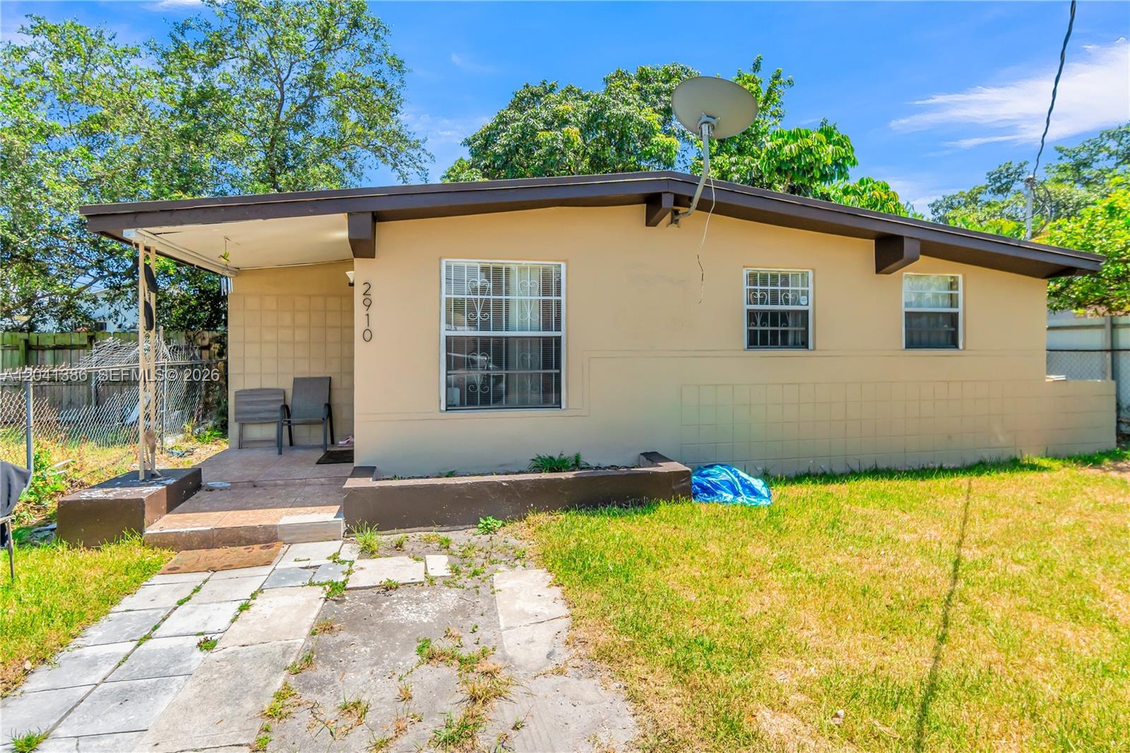 A single-story house with a tan exterior, a small covered porch, and a satellite dish — 2910 NW 47th St, Miami FL 33142, MIAMI, FL