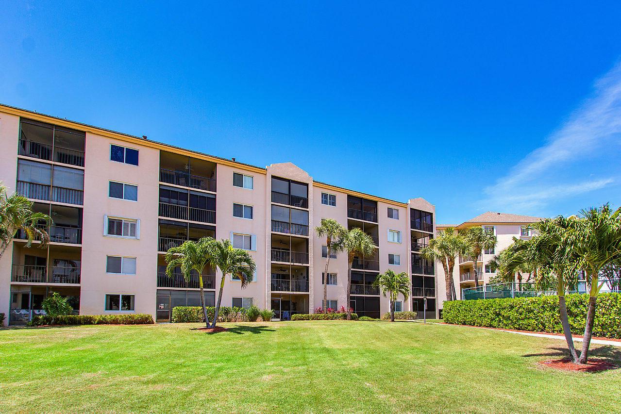 A multi-story apartment building with screened balconies overlooks a grassy lawn with palm trees — 275 Palm Avenue # A201, Jupiter FL 33477, JUPITER, FL