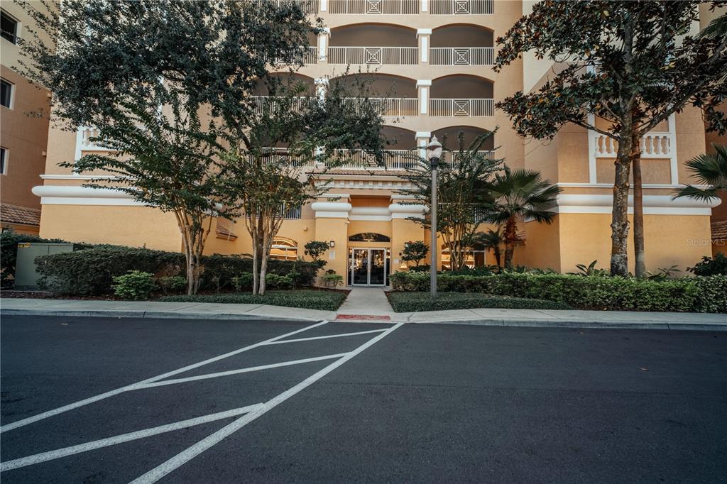 The exterior of a multi-story, tan-colored apartment building features arched balconies and a central entrance — 6336 BUFORD STREET UNIT 201, ORLANDO, FL