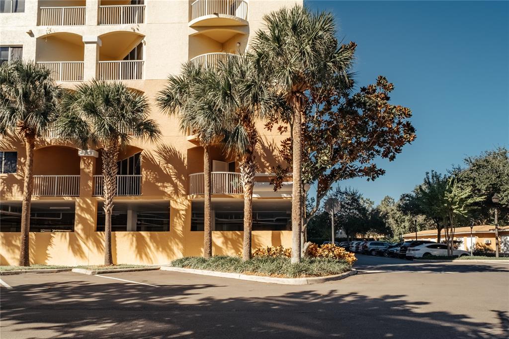 A multi-story tan apartment building features balconies and palm trees in the foreground — 6336 BUFORD STREET UNIT 201, ORLANDO, FL