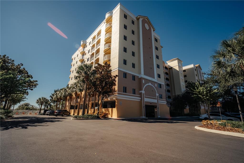 A multi-story apartment building with balconies and a parking garage entrance under a clear sky — 6336 BUFORD STREET UNIT 201, ORLANDO, FL