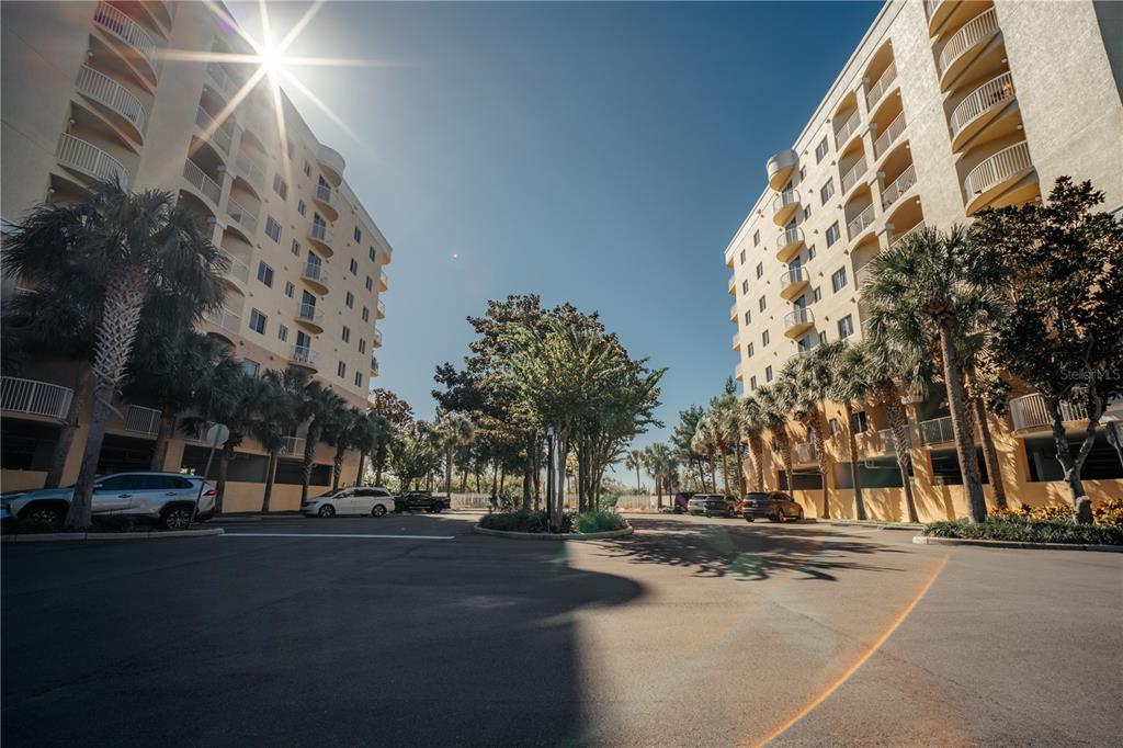 A low-angle view shows two multi-story apartment buildings flanking a paved parking lot with palm trees — 6336 BUFORD STREET UNIT 201, ORLANDO, FL