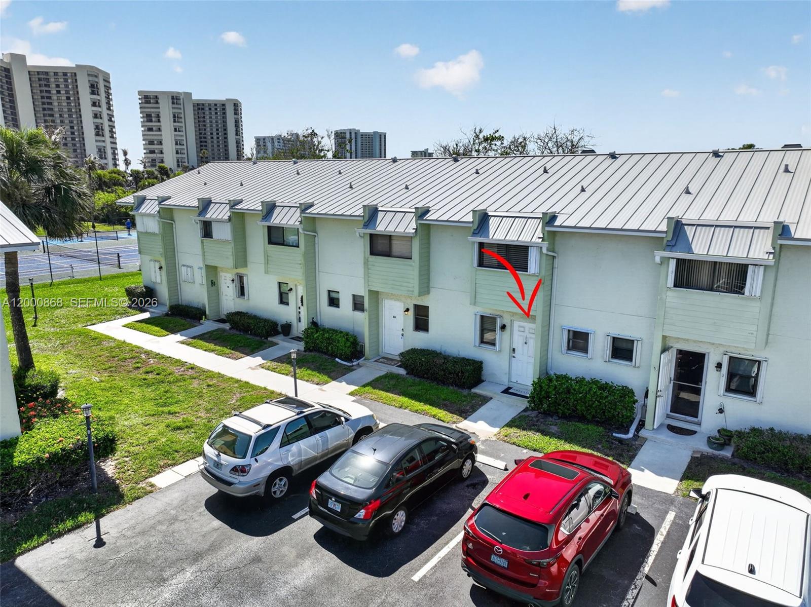 An aerial view shows a row of light green townhouses with a red arrow pointing toward a white front door — 9425 S Ocean Dr # 67, Jensen Beach FL 34957, JENSEN BEACH, FL