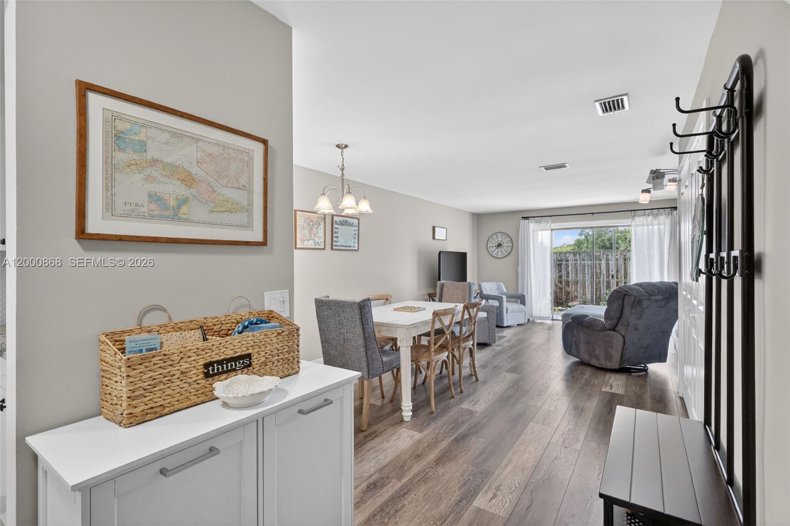 A living and dining area features wood-look flooring, a white table, and a sliding glass door — 9425 S Ocean Dr # 67, Jensen Beach FL 34957, JENSEN BEACH, FL