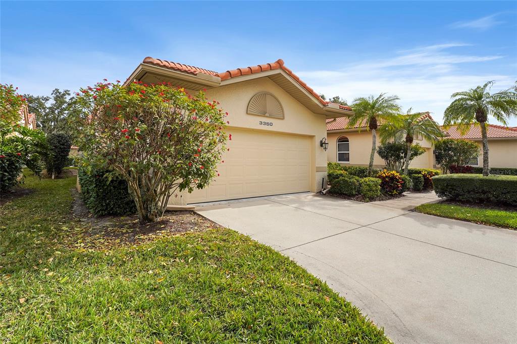 A single-story house with a beige stucco exterior, a two-car garage, and a tiled roof — 3350 W CHELMSFORD COURT UNIT 13, SARASOTA, FL