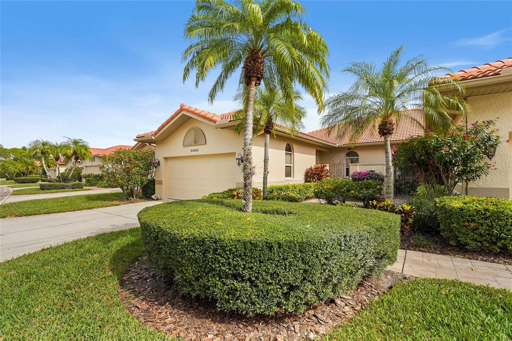 A single-story house with a tan stucco exterior, a tile roof, and a manicured hedge — 3350 W CHELMSFORD COURT UNIT 13, SARASOTA, FL