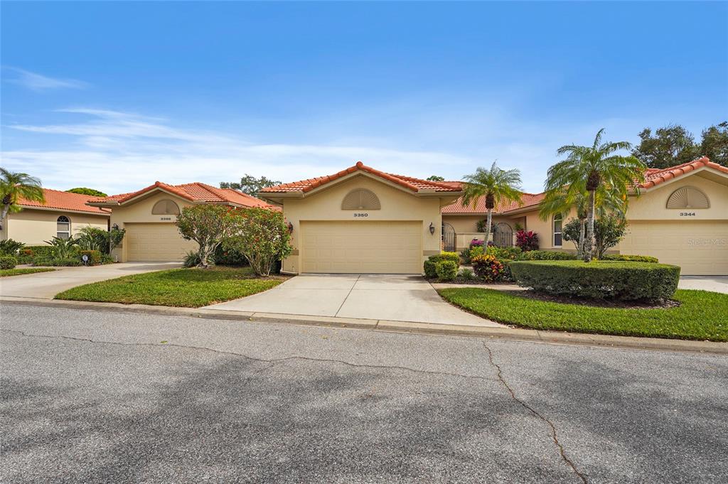 A row of three single-story suburban houses with tan stucco walls and orange tile roofs — 3350 W CHELMSFORD COURT UNIT 13, SARASOTA, FL