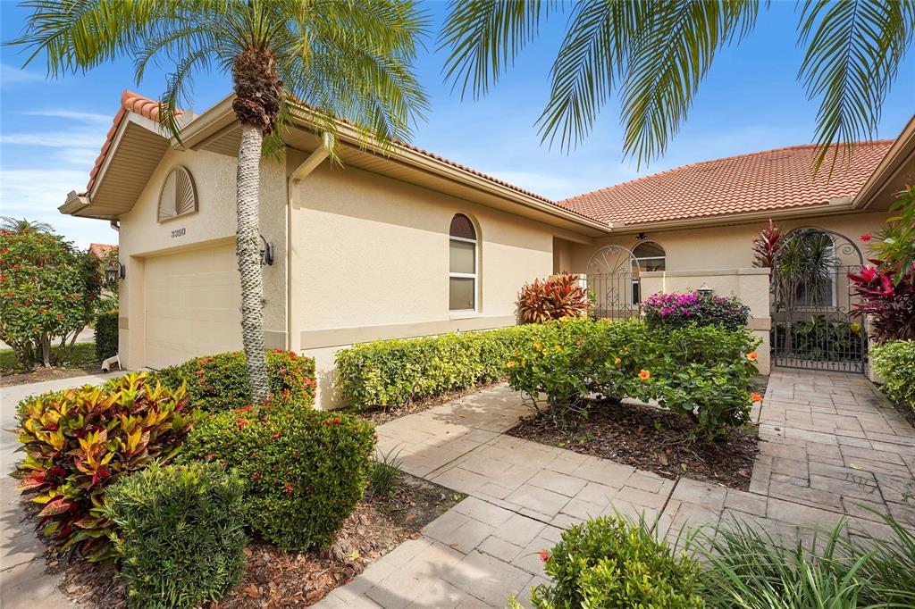A beige stucco house features a tile roof, a garage, and a paved walkway entrance — 3350 W CHELMSFORD COURT UNIT 13, SARASOTA, FL
