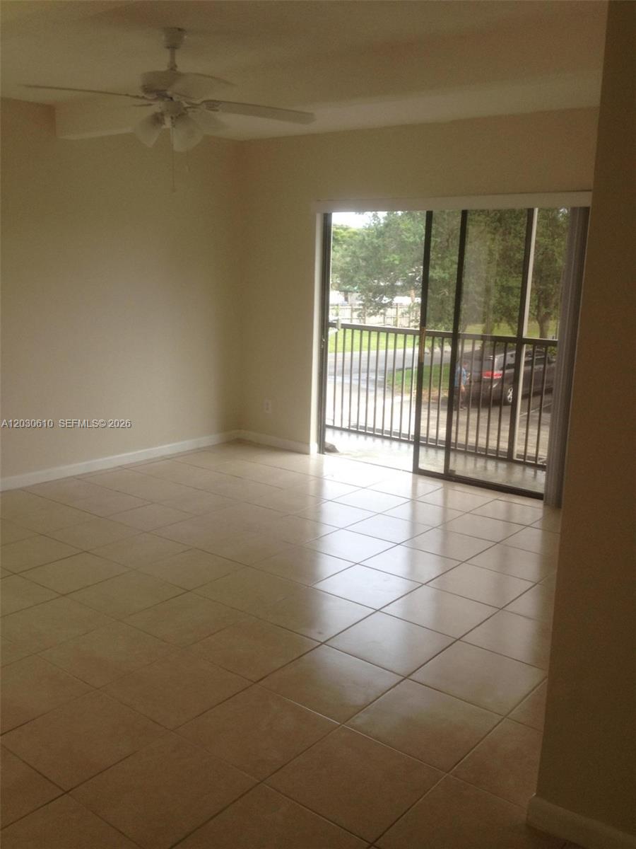 An empty room features light-colored tile flooring, a ceiling fan, and a sliding glass door — 1085 S Flagler Ave # 616, Pompano Beach FL 33060, POMPANO BEACH, FL