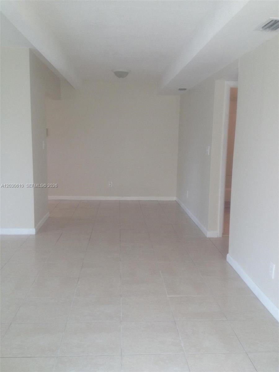 An empty room features light-colored floor tiles, beige walls, and a recessed ceiling area — 1085 S Flagler Ave # 616, Pompano Beach FL 33060, POMPANO BEACH, FL