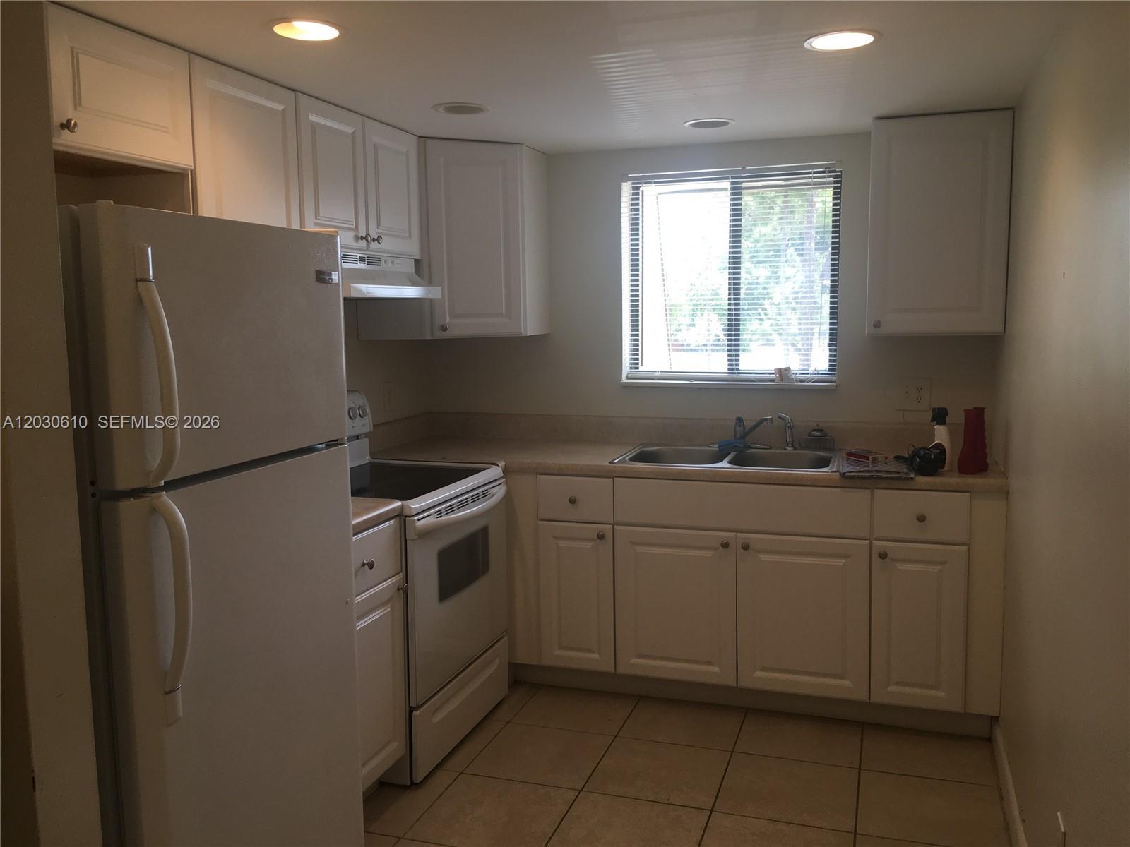 A kitchen features white cabinets, a white refrigerator, a stove, and a double sink — 1085 S Flagler Ave # 616, Pompano Beach FL 33060, POMPANO BEACH, FL