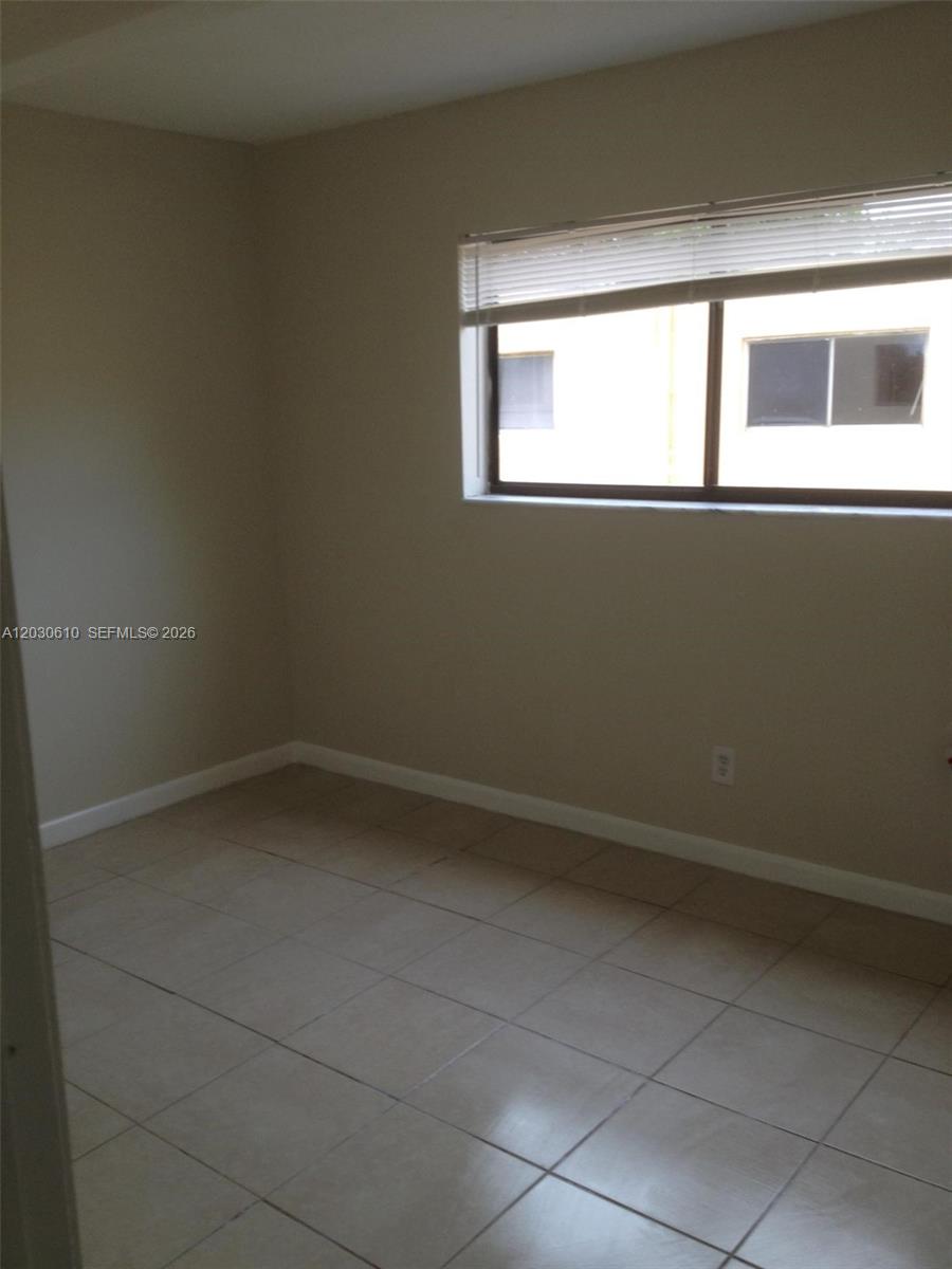 An empty room features beige walls, light-colored tile flooring, and a window with blinds — 1085 S Flagler Ave # 616, Pompano Beach FL 33060, POMPANO BEACH, FL
