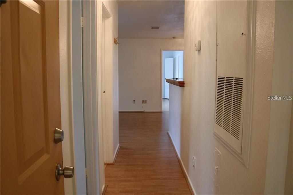 A hallway with wood-look flooring leads toward an open doorway and a kitchen pass-through — 1400 GANDY BOULEVARD N UNIT 1308, ST PETERSBURG, FL