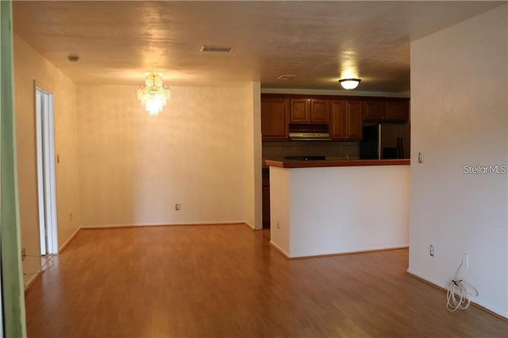 An open-concept dining area with wood-look flooring leads into a kitchen with wooden cabinets — 1400 GANDY BOULEVARD N UNIT 1308, ST PETERSBURG, FL