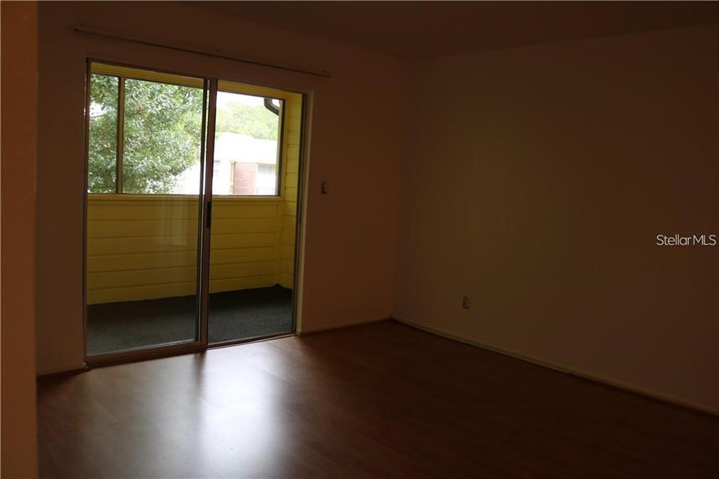 An empty room with wood-look flooring and a sliding glass door leading to a balcony — 1400 GANDY BOULEVARD N UNIT 1308, ST PETERSBURG, FL