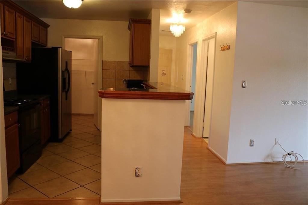 A kitchen with wood cabinets and tile flooring overlooks a living area with wood floors — 1400 GANDY BOULEVARD N UNIT 1308, ST PETERSBURG, FL